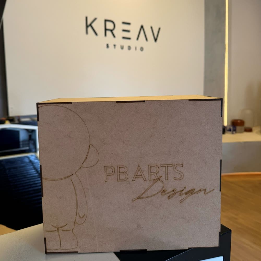 Caixa de MDF gravada diante da placa da Kreav